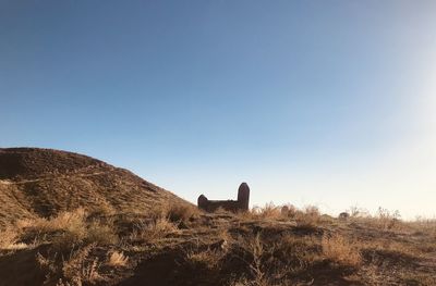 Rear view of man standing on mountain against clear blue sky