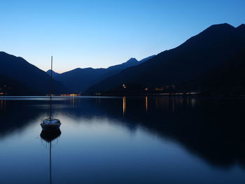 Scenic view of lake and mountains against clear blue sky