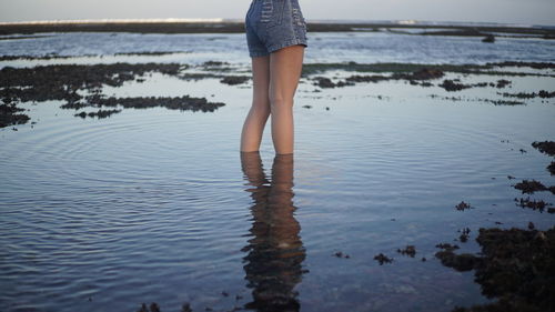 Low section of woman standing in water