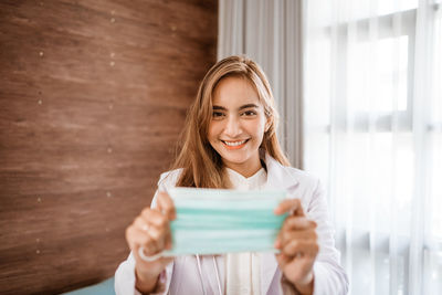 Portrait of smiling young woman holding camera