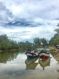 Fishing boat in lake against sky