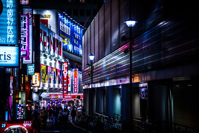 People walking on road along neon billboards on built structures