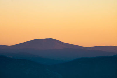 Scenic view of silhouette mountains against orange sky