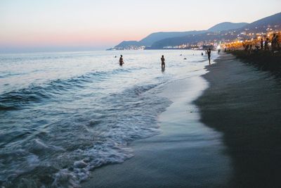 People on beach against sky during sunset