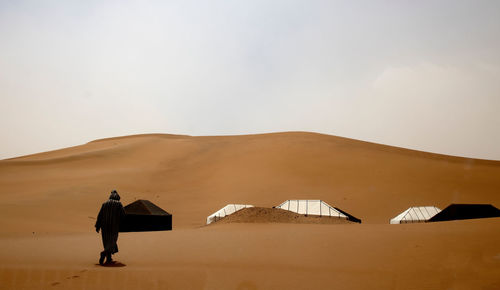 Rear view of man standing on desert against sky