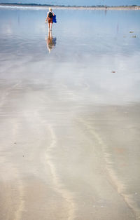 Woman walking on wet beach