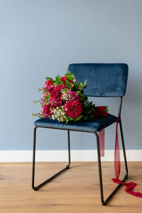 Bunch of flowers in burgundy tones on a dark blue velvet chair.