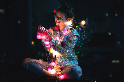 Smiling holding christmas lights in darkroom