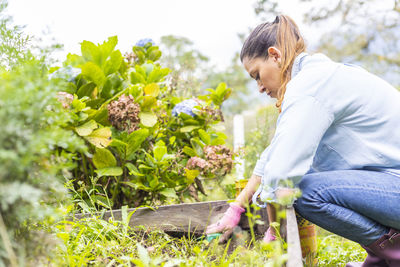 Side view of woman standing by flowering plants