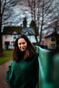 Portrait of smiling woman standing against trees