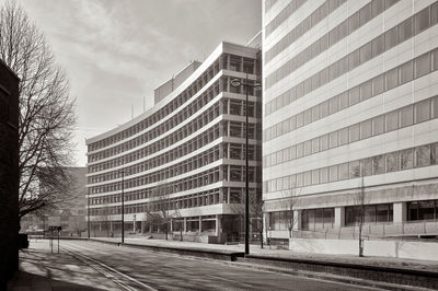 Road by buildings against sky in city