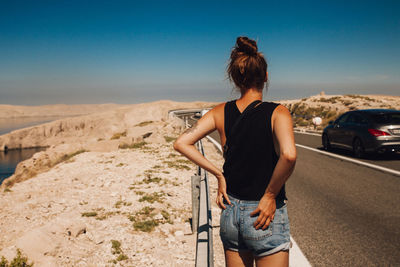 Rear view of woman standing on street against sky