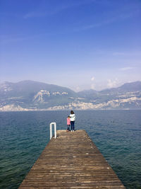 Rear view of man on pier over sea against sky