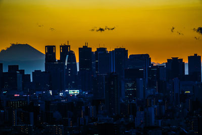 Illuminated cityscape against sky during sunset