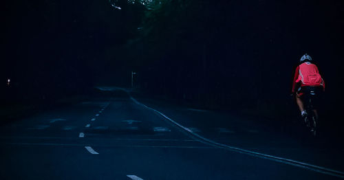 Rear view of men cycling on road in forest