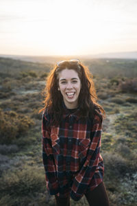 Happy woman in plaid shirt at sunset