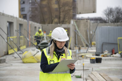 Woman construction site engineer architect worker with hard hat writes notes on the progress of work