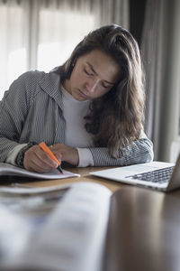 Young woman using phone while sitting on table