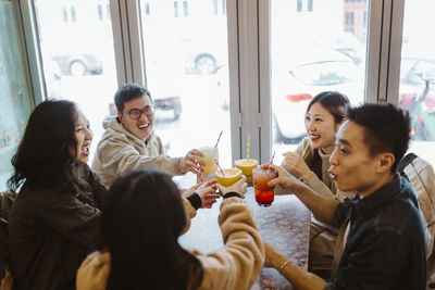 Happy multiracial male and female friends toasting drinks at restaurant