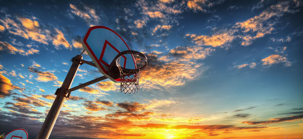 Low angle view of basketball hoop against sky during sunset