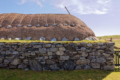 Stone wall on field against sky