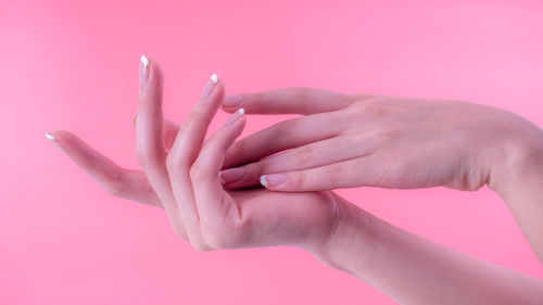 Close-up of woman hand over pink background