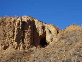 Rock formations on landscape against clear blue sky