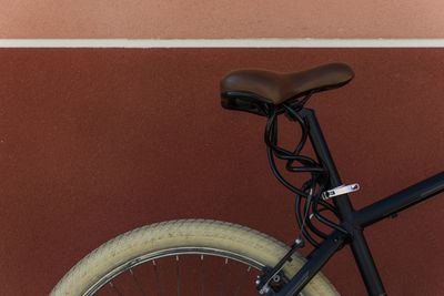 Cropped image of bicycle parked by brown wall in city