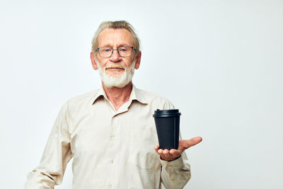 Portrait of senior man holding coffee cup against white background