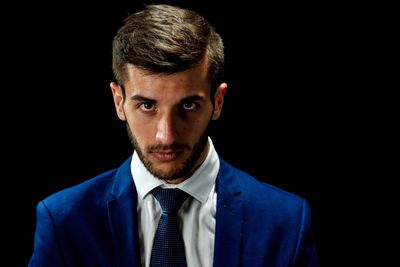 Portrait of young man against black background