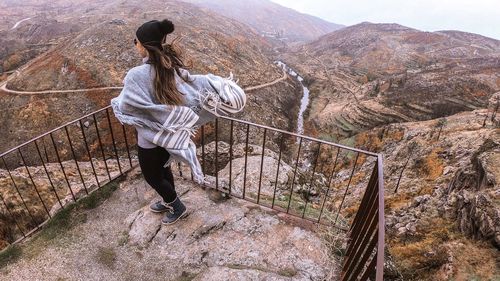 Rear view of woman standing by railing over mountains