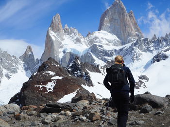 Rear view of woman hiking against snowcovered mountains