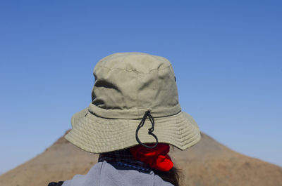 Rear view of woman wearing hat against blue sky