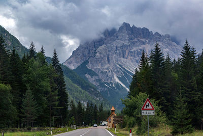 Road amidst trees and mountains against sky