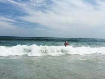 Man with daughter in sea against sky