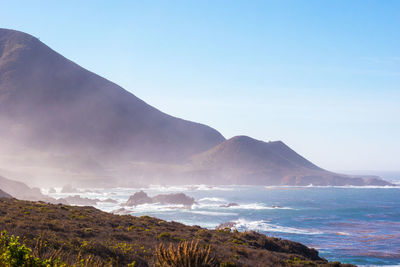 Scenic view of sea and mountains against clear sky