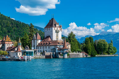 Buildings by river against sky