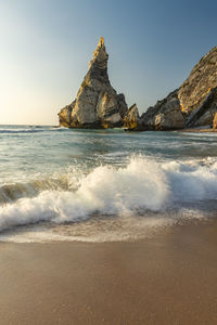 Scenic view of waves splashing at sea against sky