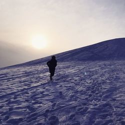 Silhouette man on snowcapped mountain against sky during sunset