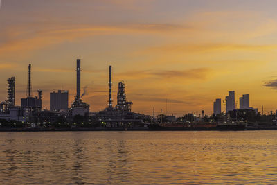 Scenic view of river by buildings against sky during sunset