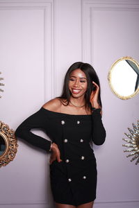 Portrait of young woman standing against wall