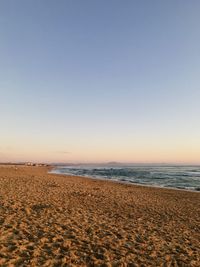 Scenic view of beach against clear sky during sunset