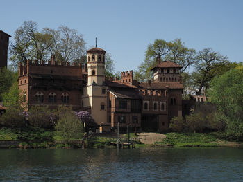 Buildings by river against clear sky