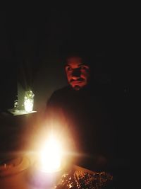 Portrait of man in illuminated dark room