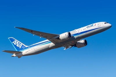 Low angle view of airplane against clear blue sky