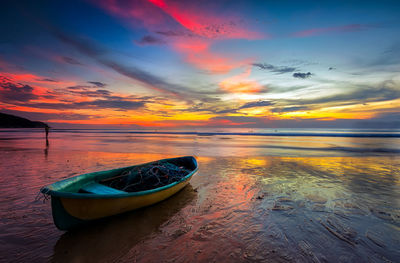 Empty fishing boat at sea shore during sunset