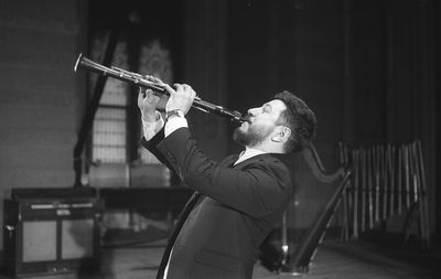 Man playing clarinet while standing at studio