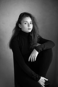 Black and white photo portrait of a serious girl in black clothes in the studio