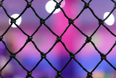 Full frame shot of fence in illuminated city at night