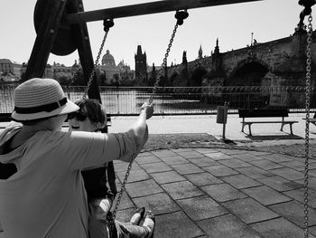 Father and son sitting on swing in city